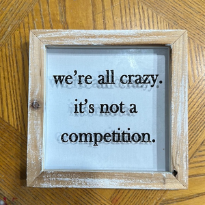 Wall sign “ We are‎ all Crazy. It’s not a Competition “
